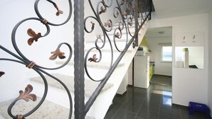 Una escalera con barandillas metálicas decoradas y un interior moderno con cocina y comedor.