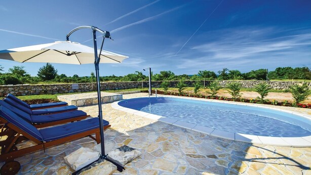 Una piscina con sillas de descanso y una pérgola.
