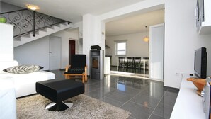 Una sala de estar moderna con un sofá, un reposapiés negro y un comedor con sillas y una mesa.