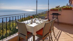 Una terraza con una mesa dispuesta para cuatro, con vistas a un paisaje marino.