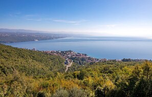 A coastal town with a view of the sea, surrounded by hills and dense greenery.