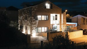A modern two-story building with multiple windows and a well-lit entrance. - Awesome Home in Novigrad With 4 Bedrooms, Sauna and Wifi (Novigrad)