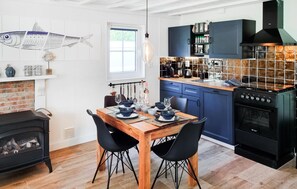 Enjoy meals in the kitchen and dining area, featuring a range, tiled backsplash, and wooden table.