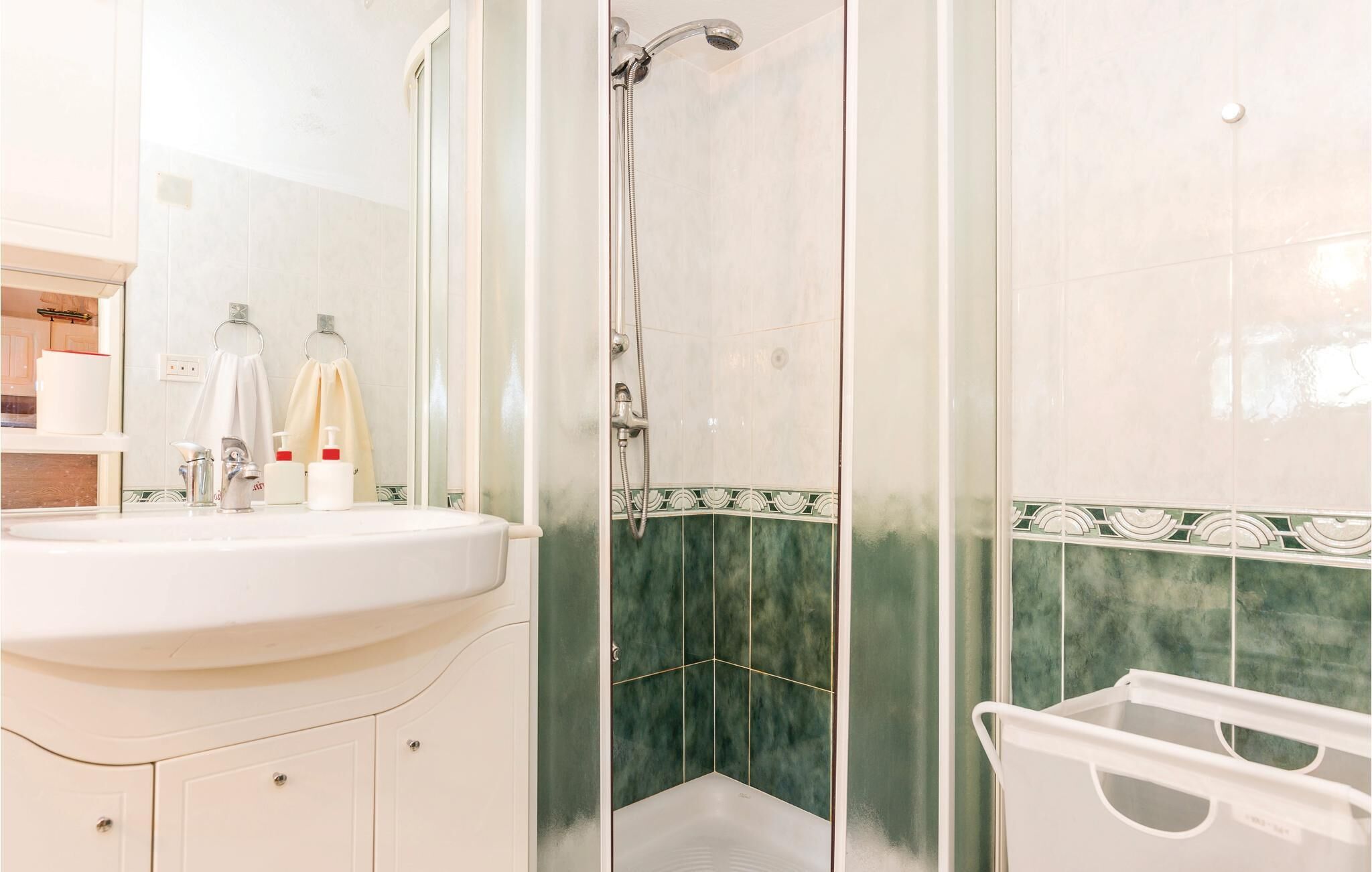 A bathroom with a sink, mirror, and shower.
