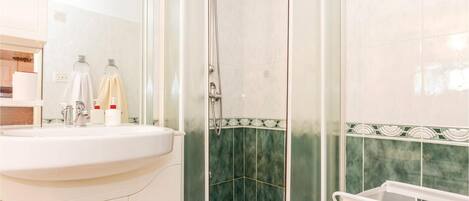 A bathroom with a sink, mirror, and shower.