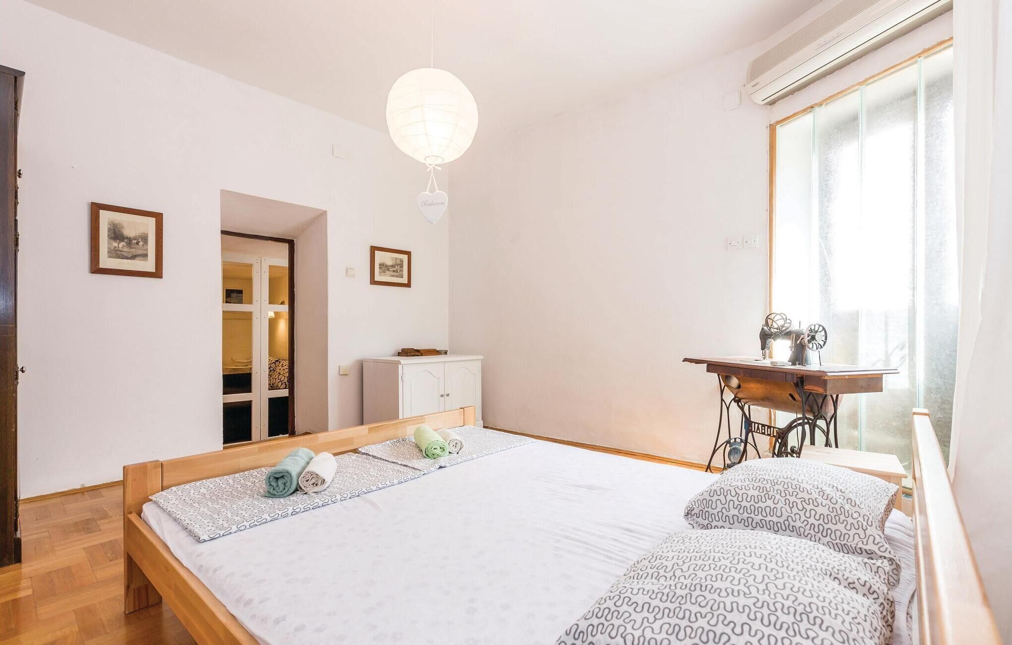 Une chambre à coucher avec un lit en bois, une machine à coudre et une fenêtre avec des rideaux.