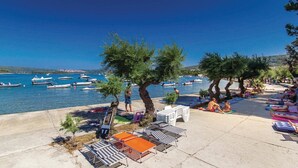 A beachside area with lounge chairs and umbrellas, a clear blue sky, and boats in the water.