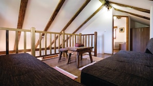 A cozy attic bedroom with a wooden staircase, a small table with decorative items, and two dark-colored sofas. - Beautiful Home in Hrnjanec With 1 Bedrooms and Wifi (Sveti Ivan Zelina)