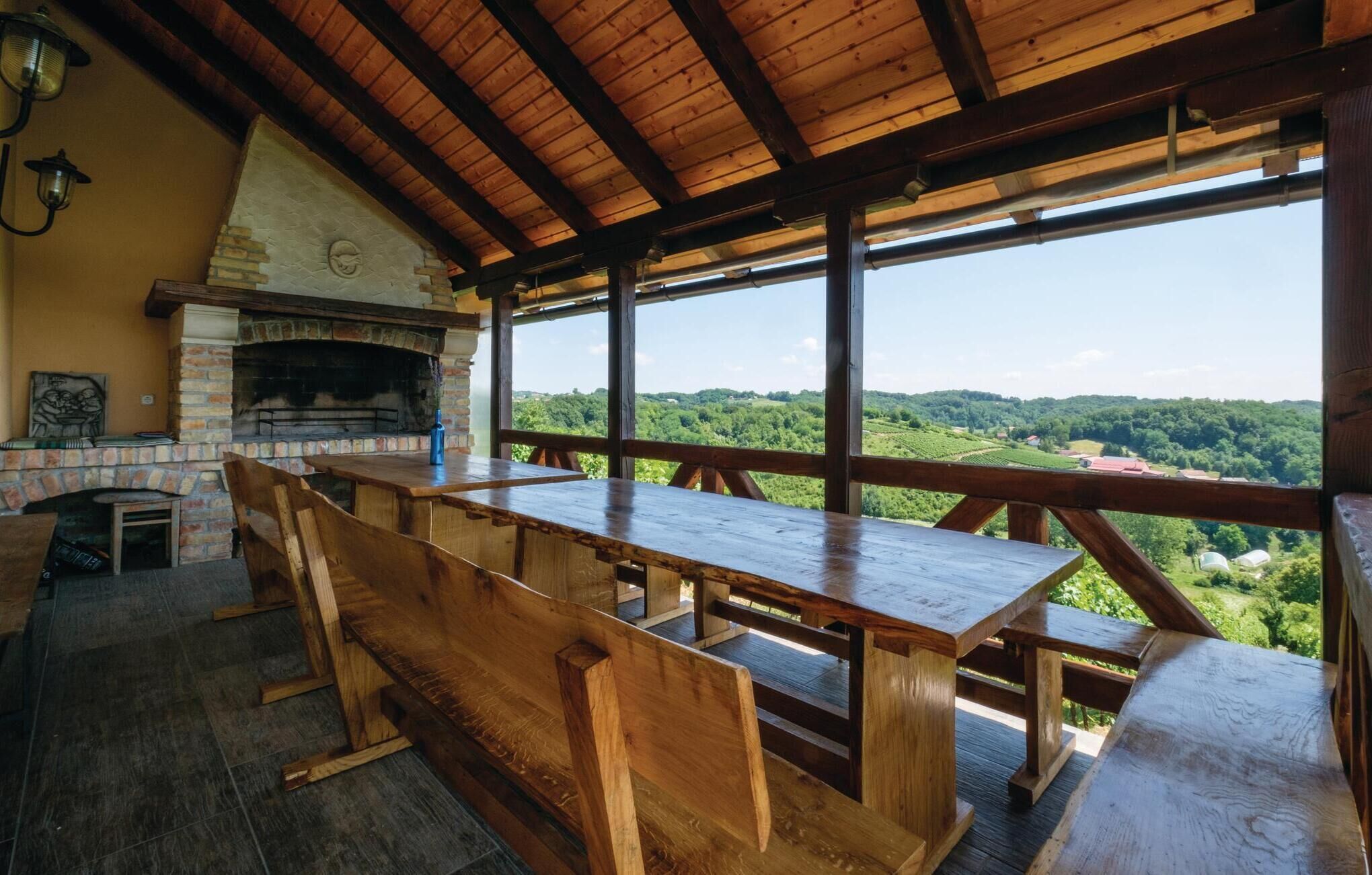 A rustic wooden dining area with a stone fireplace, overlooking a lush green landscape.
