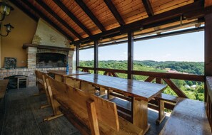 Un comedor rústico de madera con chimenea de piedra, con vistas a un paisaje verde exuberante.