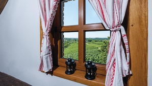 A window with a view of a green landscape, curtains, and two lanterns on the sill. - Beautiful Home in Hrnjanec With 1 Bedrooms and Wifi (Sveti Ivan Zelina)