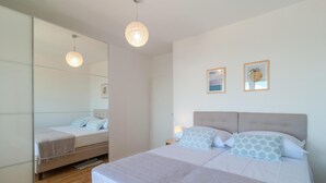 A bedroom with a large mirror, two beds with matching headboards, and two framed pictures on the wall. - Stunning Apartment in Dugi Rat With 2 Bedrooms and Wifi (Dugi Rat)