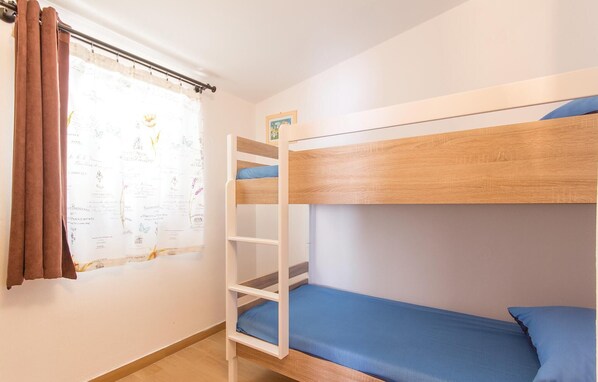 A bunk bed room with a window, curtains, and a small picture frame on the wall.