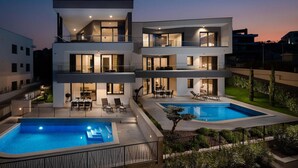 A modern multi-story house with two swimming pools, balconies, and a well-lit outdoor area. - Amazing Home in Zidarici With Outdoor Swimming Pool, Wifi and 6 Bedrooms (Malinska-Dubasnica)