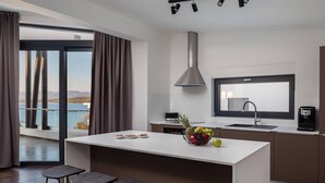 A modern kitchen with a central island, bar stools, a large window with a view, and a built-in stove. - Amazing Home in Zidarici With Outdoor Swimming Pool, Wifi and 6 Bedrooms (Malinska-Dubasnica)
