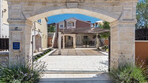 An entrance with an archway, a covered patio area, and a building with a red roof. - Stunning Home in Porec With Wifi and 2 Bedrooms (Porec)