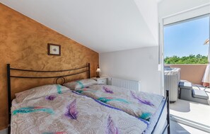 Quarto com cama, mesa de cabeceira, radiador e vista para o exterior.