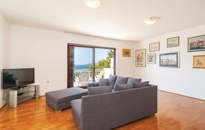 A modern living room with a grey sofa, a flat-screen TV, and a balcony with a view of the sea. - Amazing Home in Trogir With Wifi and 3 Bedrooms (Trogir)