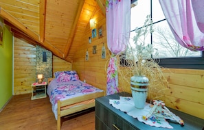 A cozy wooden cabin bedroom with a bed, a dresser, a vase with dried plants, and a window with curtains. - Awesome Home in Donja Zelina With 3 Bedrooms, Wifi and Outdoor Swimming Pool (Sveti Ivan Zelina)