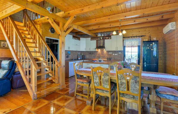 A wooden interior with a dining area, kitchen, and staircase.