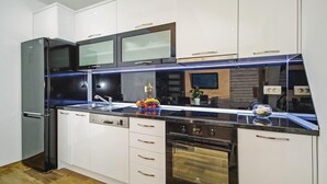 A modern kitchen with white cabinets, a black refrigerator, a stainless steel sink, and a built-in oven. - Awesome Home in Umcani With Wifi and 9 Bedrooms (Vrgorac)