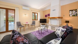 Ein Wohnzimmer mit einer Couch, einem Fernseher, einem Kamin und einem Essbereich mit Stühlen und einem Tisch.
