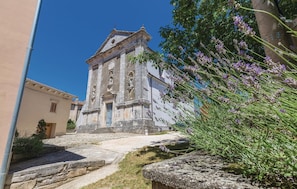 A historic church with a bell tower, stone steps leading up to the entrance, and a garden with lavender. - Nice Home in Kmacici With Outdoor Swimming Pool, Wifi and 3 Bedrooms (Tinjan)