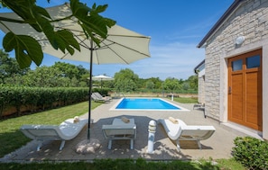 A swimming pool with lounge chairs and an umbrella, surrounded by a stone building and greenery. - Nice Home in Kmacici With Outdoor Swimming Pool, Wifi and 3 Bedrooms (Tinjan)