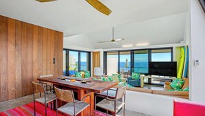 Uma sala de estar moderna com uma mesa de jantar de madeira, cadeiras, um sofá e uma televisão.