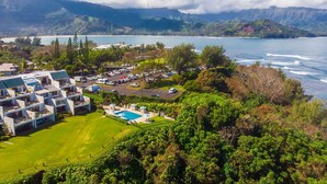 Um resort com piscina, vários edifícios e vista para o oceano e montanhas.