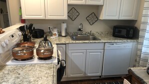 A kitchen with white cabinets, a stove, a microwave, and a dishwasher.