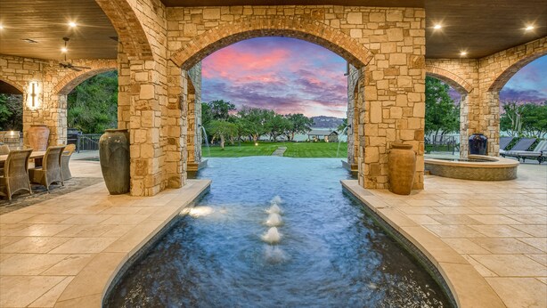 Arc de pedra que dona a una piscina amb vista a un camp de golf i arbres.