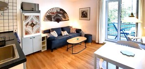 A compact living space with a kitchenette, a sofa, a small table, and a view of the outdoors.
