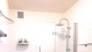 A bathroom with a bathtub, shower, toilet, and a red rug. - Right in the middle and yet quiet (München)