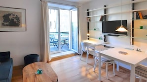 A modern apartment with a dining area, a sofa, a small table, and a balcony with outdoor furniture. - Right in the middle and yet quiet (München)