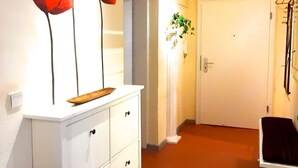 A hallway with a white cabinet, a door, and a plant. - Right in the middle and yet quiet (München)
