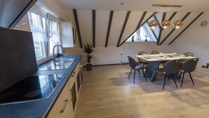 Une cuisine moderne dotée d’un grand îlot central, d’un coin repas avec une table et des chaises, et d’une plante en pot.