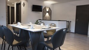 Un espace repas moderne avec une table rectangulaire dressée pour quatre personnes, entourée de quatre chaises.