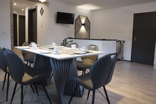 A modern dining area with a rectangular table set for four, surrounded by four chairs.
