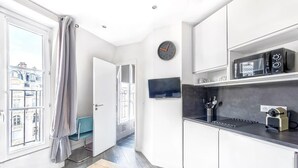A modern kitchen with white cabinets, a black countertop, and a clock on the wall. - Studio Mac Mahon - Champs Elysees by B'Your Home (Paris)