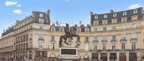 A historic building with classical architecture, a central statue, and a well-maintained plaza.