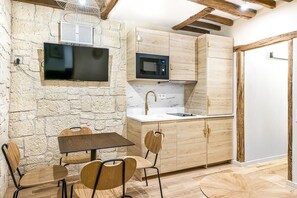 Uma cozinha compacta com parede de pedra, televisão de tela plana, micro-ondas e armários de madeira.
