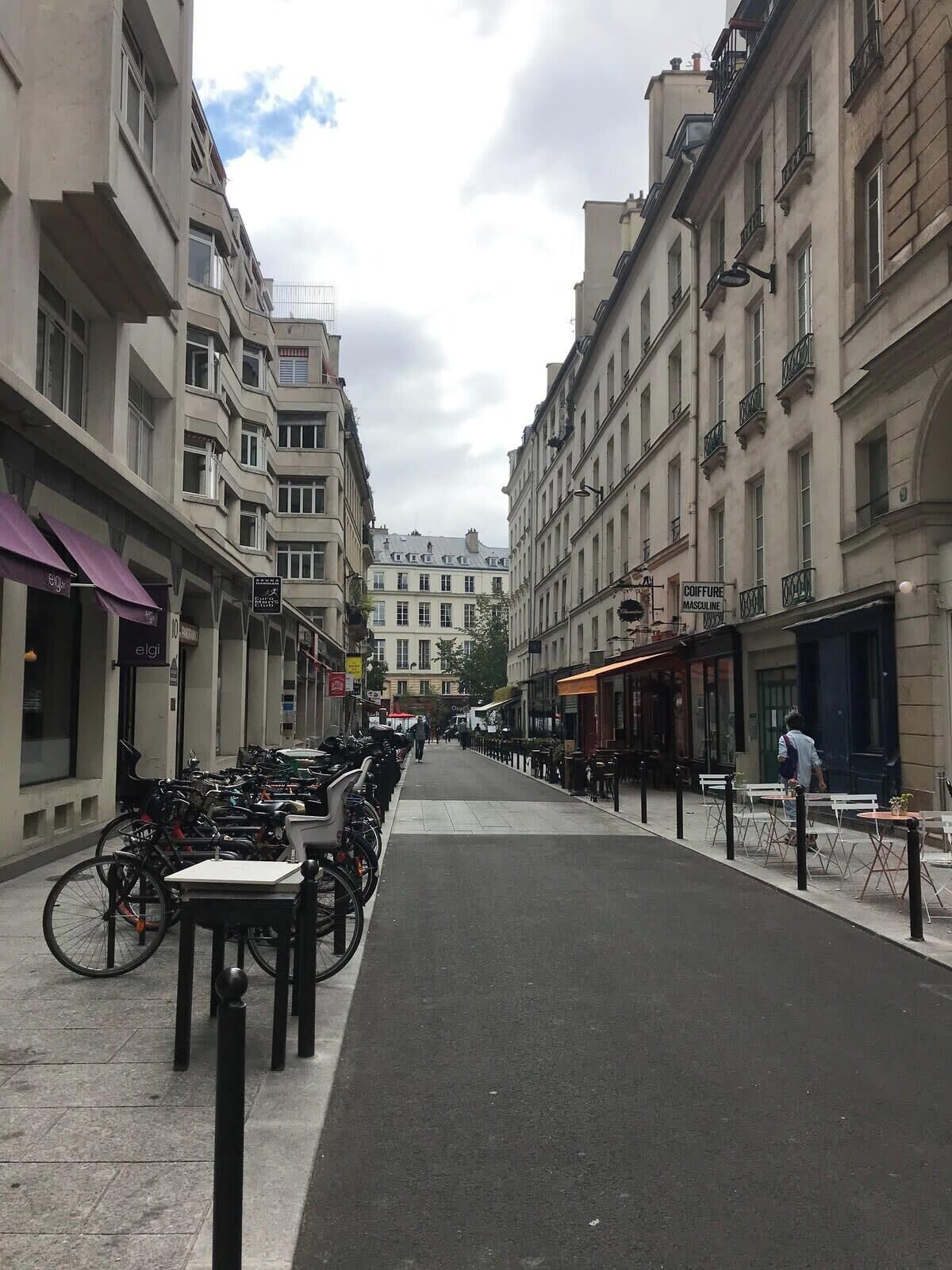 Une rue bordée d’immeubles, dont certains sont dotés de balcons, et une rangée de vélos garés sur le trottoir.