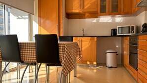 A modern kitchen with wooden cabinets, a microwave, a sink, and a trash bin. - Oceanus Executive Apartamento (Ponta Delgada)