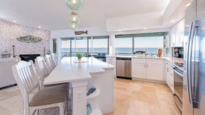 A modern kitchen with a large island, white cabinetry, stainless steel appliances, and a view of the sea. - Bay beauty with heated pool, spa, games, ping pong (Holmes Beach)