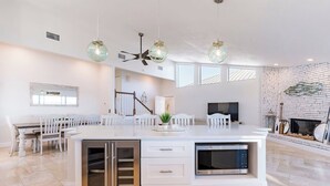 A modern kitchen with a central island, white cabinetry, a built-in microwave, and a stainless steel refrigerator. - Bay beauty with heated pool, spa, games, ping pong (Holmes Beach)