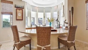 A dining area with a round table and three wicker chairs. - 🏝️Chic villa on the lake! 3 bed 3 bath, Golf, bbq & fun in the sun 🌵🏝️🍦👙 (Indio)