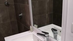 A modern bathroom with a white sink, a mirror, and a towel.