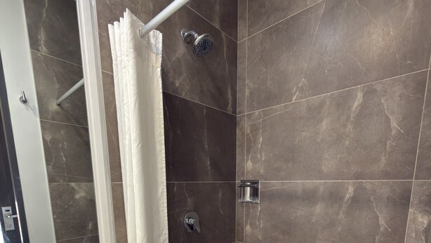 A bathroom with a white sink, a shower with a glass enclosure, and dark tiled walls.