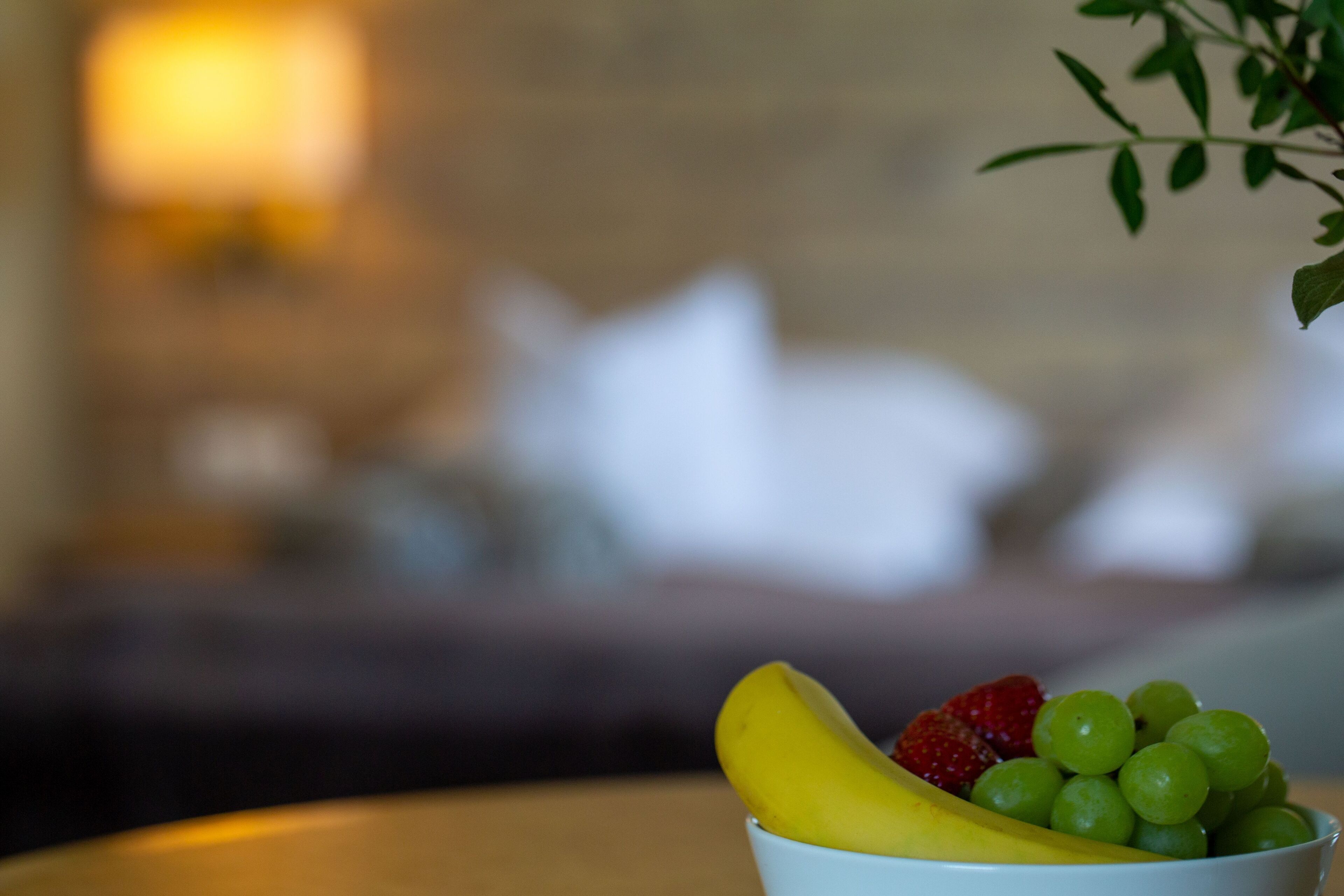 A bowl of fruit on a table with a blurred background.